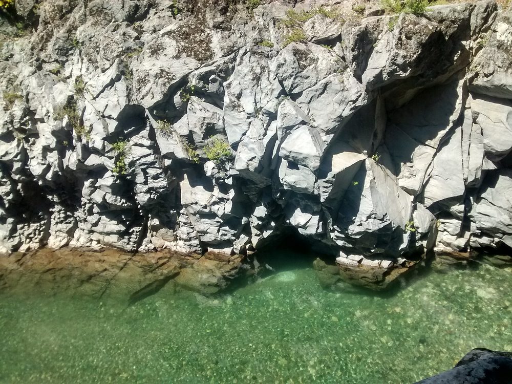 Pozón de aguas verdes bajo paredes de roca basáltica en Radal Siete Tazas